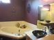 A bathroom with a corner soaking tub, plum walls with decorations, and black vessel sink at 4288 Silver Hill Dr, Greenwood, IN 46142