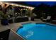 Backyard pool illuminated at night, featuring a covered lounge area with a fireplace at 434 Sheffield Ct, Carmel, IN 46032