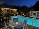 Outdoor pool area with table, basketball hoop, and a covered pergola with string lights at night at 434 Sheffield Ct, Carmel, IN 46032