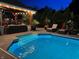 Backyard pool illuminated at night, featuring a covered lounge area with a fireplace at 434 Sheffield Ct, Carmel, IN 46032