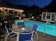 Outdoor pool area with table, basketball hoop, and a covered pergola with string lights at night at 434 Sheffield Ct, Carmel, IN 46032