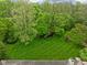 An aerial view showcasing backyard with mature trees, lush green grass, and playset at 470 Mill Farm Rd, Noblesville, IN 46062