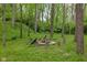 A secluded firepit area with log seating, nestled among mature trees, creating a cozy outdoor space at 470 Mill Farm Rd, Noblesville, IN 46062