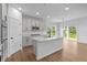 Bright kitchen with white cabinets, stainless appliances, a kitchen island, and a sliding glass door to the backyard at 5032 Carmine St, Brownsburg, IN 46112