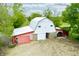 Aerial view of a barn with a white roof and red sides, featuring a spacious dirt yard and surrounding greenery at 5335 W 550 S, Trafalgar, IN 46181