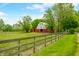 Picturesque red barn on a lush green property, complete with a wooden fence under a blue sky at 5335 W 550 S, Trafalgar, IN 46181