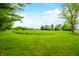 A large grassy field under a beautiful blue sky, perfect for building or recreation with distant trees and fencing at 5335 W 550 S, Trafalgar, IN 46181