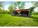 Open shed housing a tractor and various equipment, providing ample storage and functional workspace at 5335 W 550 S, Trafalgar, IN 46181