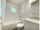 Bright bathroom with a white vanity, toilet, and tub with white subway tile at 6150 E 25Th St, Indianapolis, IN 46219