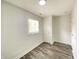 Bedroom featuring wood-look flooring, white walls, with a bright window and white door at 6150 E 25Th St, Indianapolis, IN 46219