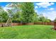 Spacious, fenced backyard with a playset and mature trees, perfect for outdoor activities and relaxation at 6609 Fountain Springs Blvd, Indianapolis, IN 46236