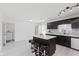 Bright kitchen showcasing an island with seating, stainless appliances, dark cabinets, and white countertops at 6703 Wimbledon Dr, Zionsville, IN 46077