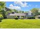 Charming ranch-style house featuring a lush lawn, mature trees, and manicured landscaping at 7035 Creekside Ln, Indianapolis, IN 46220