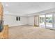 Spacious living room with carpet, brick fireplace, and sliding doors to the sunroom providing a seamless flow at 7035 Creekside Ln, Indianapolis, IN 46220