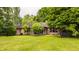 Landscaped backyard showcases the rear exterior of the brick home with lush greenery and trimmed trees at 7887 Meadowbrook Dr, Indianapolis, IN 46240