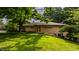 Well-maintained one-story home with brick facade, mature trees, and green lawn at 7887 Meadowbrook Dr, Indianapolis, IN 46240