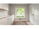 Bright laundry room with white cabinets, marble counters, a sink and a window with a view of the yard at 7887 Meadowbrook Dr, Indianapolis, IN 46240