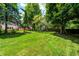 Green back yard with lush lawn, patio, fence, and mature trees at 9158 Oak Knoll Ln, Fishers, IN 46037