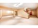 Spacious finished basement with carpet floors, stairs and warm lighting at 9158 Oak Knoll Ln, Fishers, IN 46037