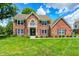 Charming two-story brick home with manicured lawn, black shutters, and classic architectural details at 9158 Oak Knoll Ln, Fishers, IN 46037