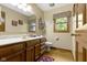 Bathroom featuring a double sink vanity with wood cabinets and a decorative mirror and window at 974 Arrowwood Dr, Carmel, IN 46033