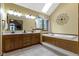 This primary bathroom has a skylight, a large soaking tub, a window, and double sinks with wood cabinets at 974 Arrowwood Dr, Carmel, IN 46033