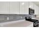 Close up of kitchen with white cabinets, stainless microwave, sleek countertops, and tile backsplash at 104 Maxim Ct, Cumberland, IN 46229
