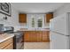 Functional kitchen with classic cabinets, white fridge, and black stove against neutral walls at 1124 S Lockburn St, Indianapolis, IN 46241