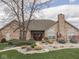 Beautiful home featuring a stone facade, double-door entry, mature tree, and lush, landscaped yard at 1130 Deerbrook Trl, Greenwood, IN 46142