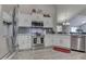 Modern kitchen featuring stainless steel appliances, white cabinetry, gray backsplash, and a view to the living room at 1130 Deerbrook Trl, Greenwood, IN 46142
