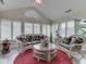 Bright sunroom with vaulted ceilings, large windows with shutters, and wicker furniture set on a red rug at 1130 Deerbrook Trl, Greenwood, IN 46142