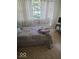 Inviting bedroom with natural light, featuring an ornate window, quilt-covered bed, desk and chair at 1212 River Heights Dr, Indianapolis, IN 46240