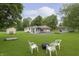 Large backyard featuring a fire pit with chairs and mature trees, with a house and shed in the background at 125 S Alfonte St, Ingalls, IN 46048