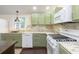 Well-lit kitchen features stainless appliances, granite countertops, green cabinets and dark-stained wood flooring at 125 S Alfonte St, Ingalls, IN 46048