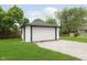 Detached garage with a white door, gravel driveway, and well-maintained lawn, providing ample parking space at 1502 Burdsal Pkwy, Indianapolis, IN 46208