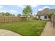 Grassy backyard with a tall wooden fence and a small out building at 1526 Carrollton Ave, Indianapolis, IN 46202
