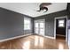 Bedroom with gray walls, wood floors, modern ceiling fan, and a door leading to a balcony at 1526 Carrollton Ave, Indianapolis, IN 46202
