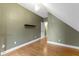 Attic bedroom featuring hardwood floors, olive-green walls, and a small black shelf at 1526 Carrollton Ave, Indianapolis, IN 46202