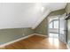 An attic room with hardwood floors and a walk out to a small porch with light at 1526 Carrollton Ave, Indianapolis, IN 46202