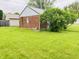 Rear view of detached garage with brick siding and an adjacent green bush in the yard at 1739 Crystal St, Anderson, IN 46012