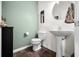 Stylish half bath featuring a pedestal sink, modern fixtures, and green accent wall at 1893 Glenmoor Ct, Columbus, IN 47201