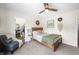 Well-lit bedroom with wood bed frame, neutral carpet, and a comfy chair with throw blanket at 1893 Glenmoor Ct, Columbus, IN 47201