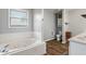 Bathroom showcasing a soaking tub with white tile surround and wood-look flooring at 2 E Quail Wood Ln, Westfield, IN 46074