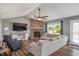 Open living room with fireplace, a large window, hardwood floors, and a comfortable sectional sofa with a ceiling fan at 2 E Quail Wood Ln, Westfield, IN 46074