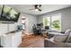 Cozy living room featuring hardwood floors, a ceiling fan, a TV, and a comfortable gray sofa with natural light from the window at 2 E Quail Wood Ln, Westfield, IN 46074