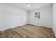 This vacant bedroom features light wood flooring, white walls, and a window to bring in the natural light at 2009 Friendship Dr, Indianapolis, IN 46217
