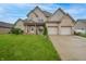 Inviting two-story brick home with a lush green lawn, mature landscaping, and a convenient two-car garage at 3247 Moonlight Ct, Columbus, IN 47203