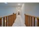 Hallway view with wood railing and carpet, leading to a bathroom at 3247 Moonlight Ct, Columbus, IN 47203