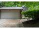 Attached two-car garage featuring a gray door and brick siding with lush greenery at 35 Osage Ct, Columbus, IN 47201