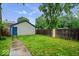 Enclosed backyard featuring grass, a wooden fence, and access to the detached garage at 3658 Graceland Ave, Indianapolis, IN 46208